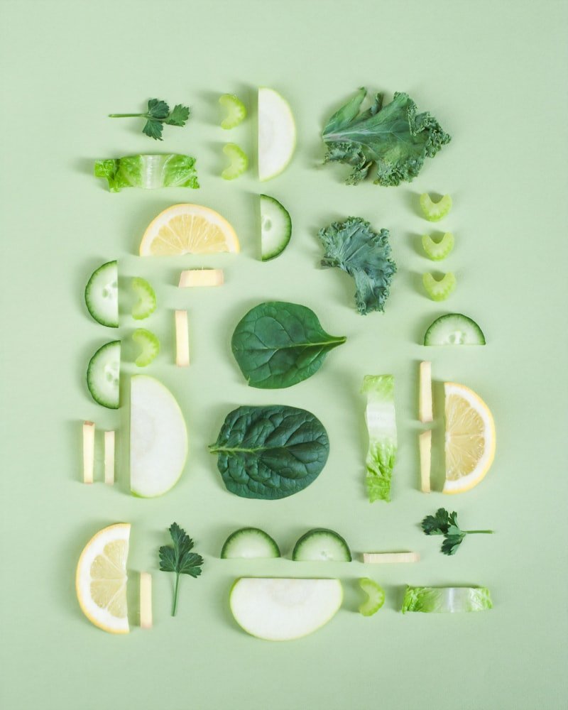 Editorial flat-lay of fresh greens, leafy herbs and citrus on a sage background — botanical foundations of naturopathic medicine