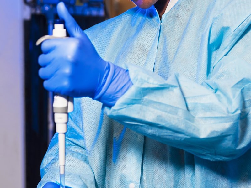 Lab technician in PPE handling a precision pipette — comprehensive functional and conventional lab testing